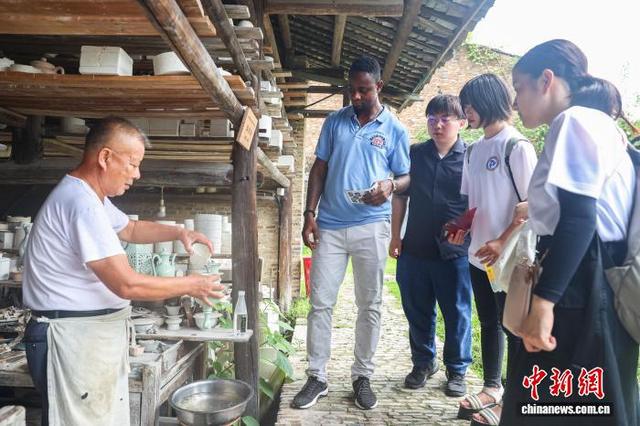 资料图为中外游客在景德镇陶阳里历史文化街区的徐家窑及作坊群内，聆听陶瓷造型大师张茂生介绍景德镇瓷器。中新社记者 刘力鑫 摄